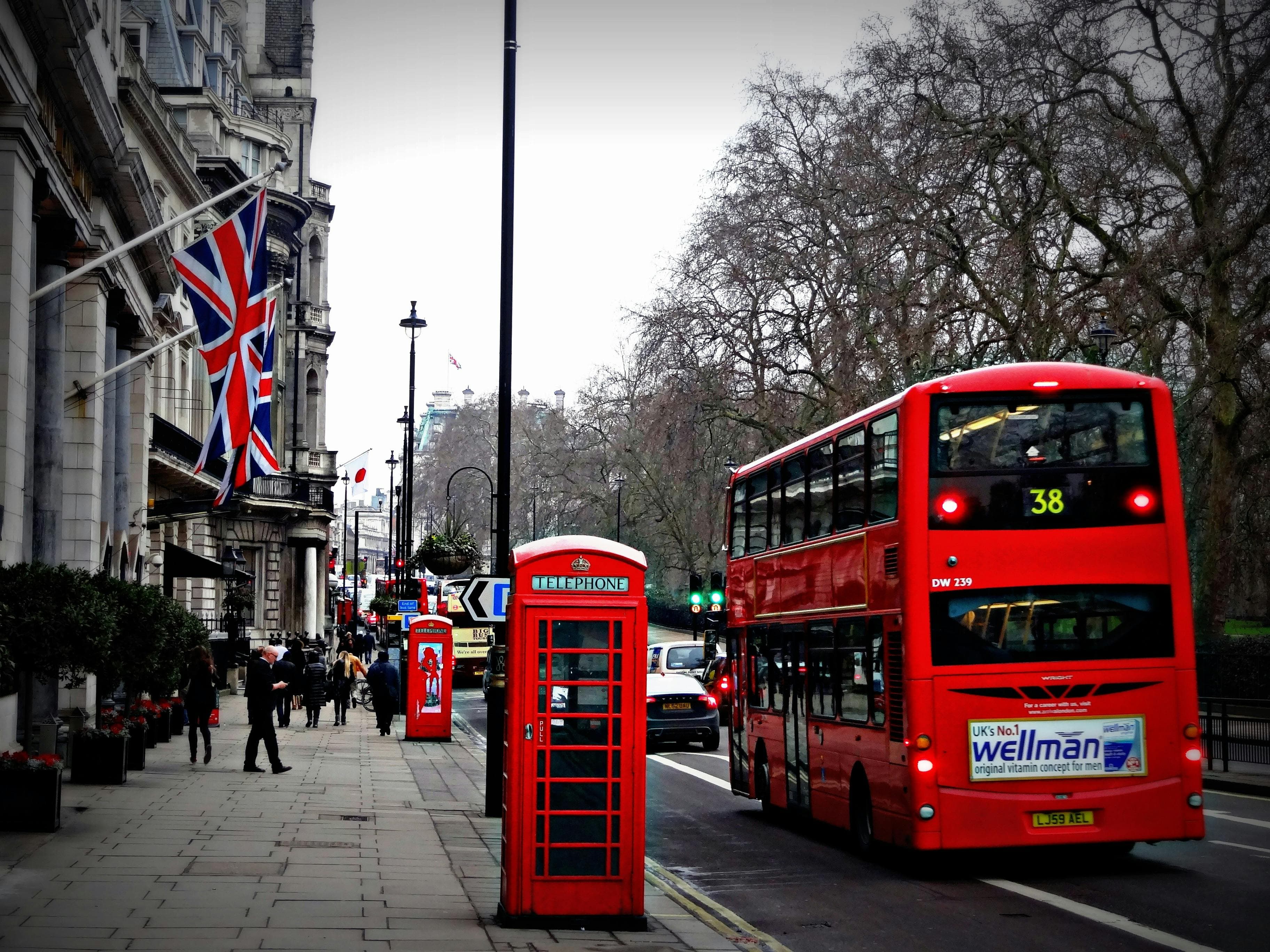 Red double-decker bus and telephone booth on a London street with a Union Jack flag.