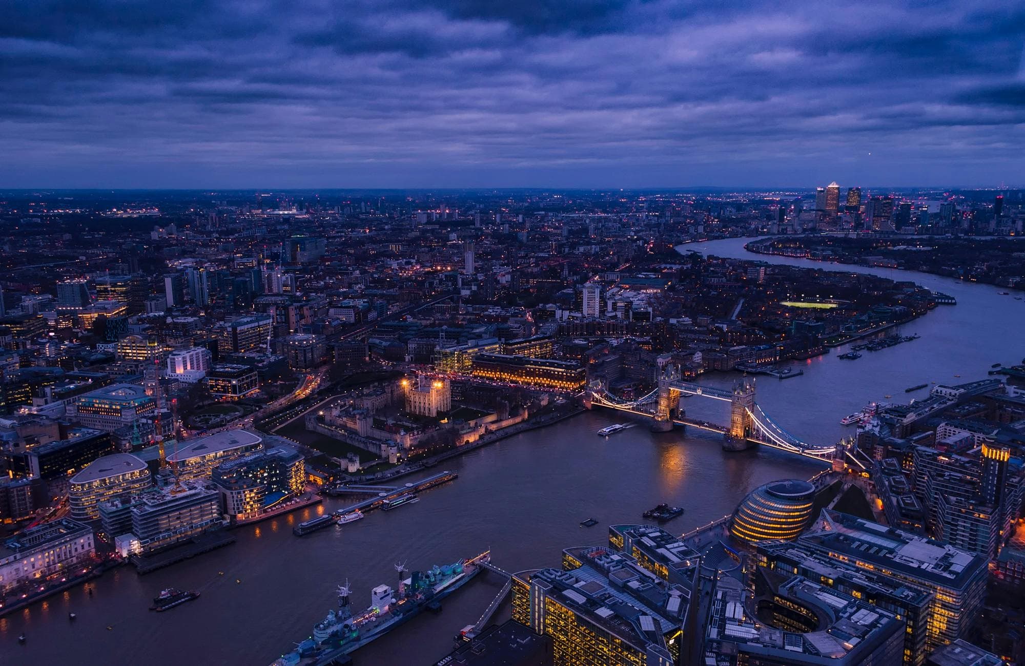 Aerial view of illuminated Tower Bridge and the River Thames in London at night.